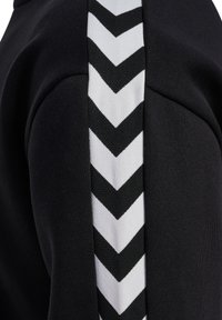 Tissu noir avec une bande blanche verticale présentant un motif chevron noir répété au centre.