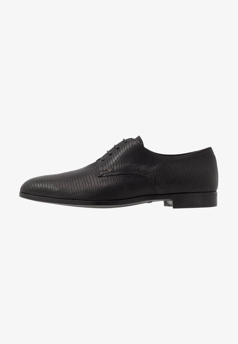 Chaussure habillée en cuir noir avec un motif texturé, bout arrondi et design à lacets. Elle présente une semelle plate et lisse ainsi que des accents minimalistes.