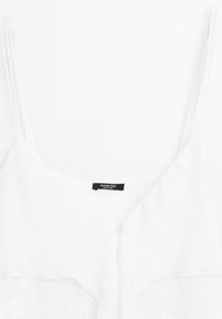 Weiße Leinen-Camisole mit dünnen Trägern, einem V-Ausschnitt und einem Knopfverschluss. Das Etikett trägt die Aufschrift "Massimo Dutti, Hergestellt in China."