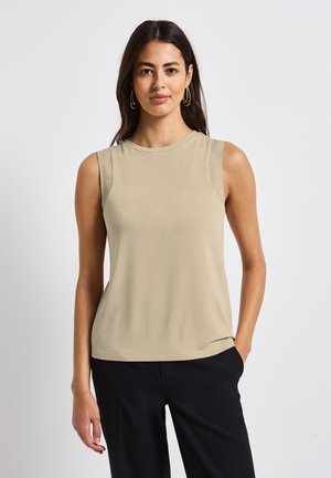 Top senza maniche in beige chiaro, realizzato in un tessuto morbido. Presenta una scollatura rotonda e un design aderente, abbinato a pantaloni neri.