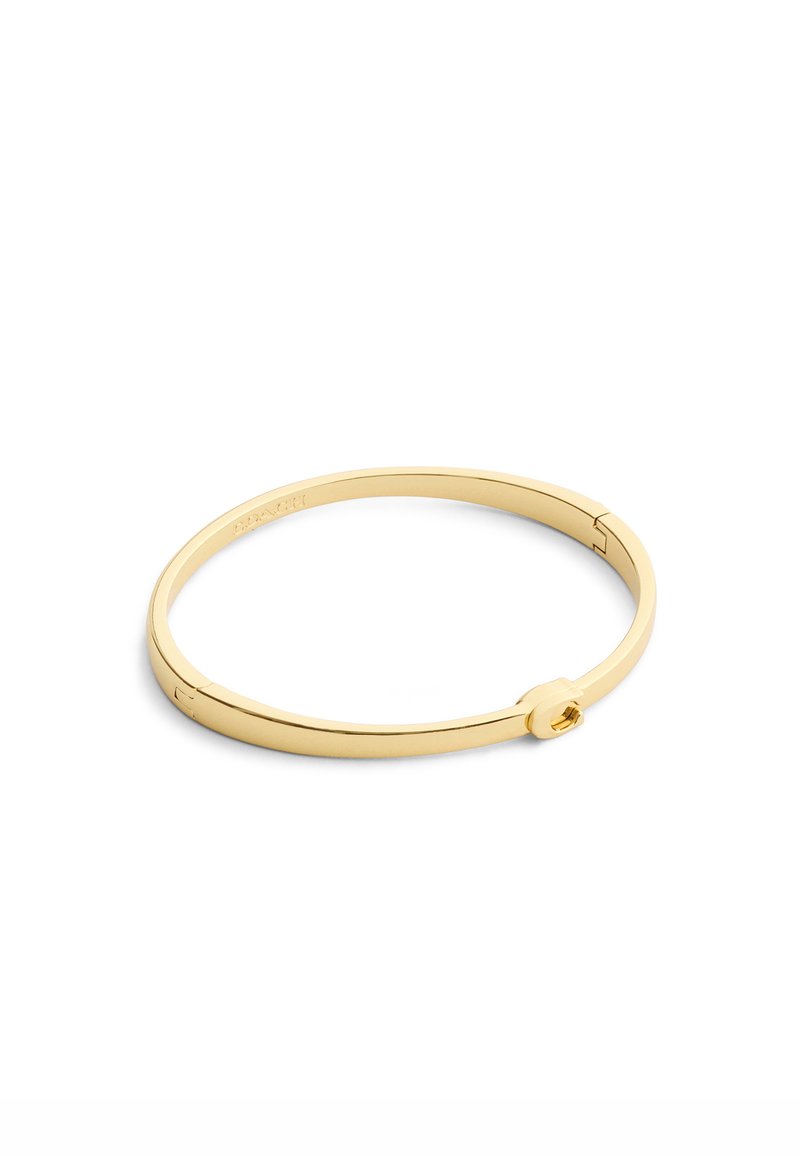 Bracciale rigido in metallo color oro con una forma rotonda elegante. Presenta una chiusura sicura con un piccolo dettaglio accentato circolare. Superficie liscia.