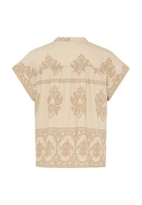 Blouse beige à manches courtes avec motifs floraux et ornementaux marron clair, petit col et coupe ample vue de dos.