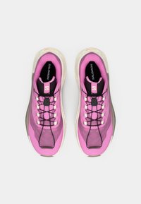 Baskets de sport roses avec une tige en maille, des lacets noirs et une semelle texturée. Détails notables incluent un logo de marque et un col rembourré.