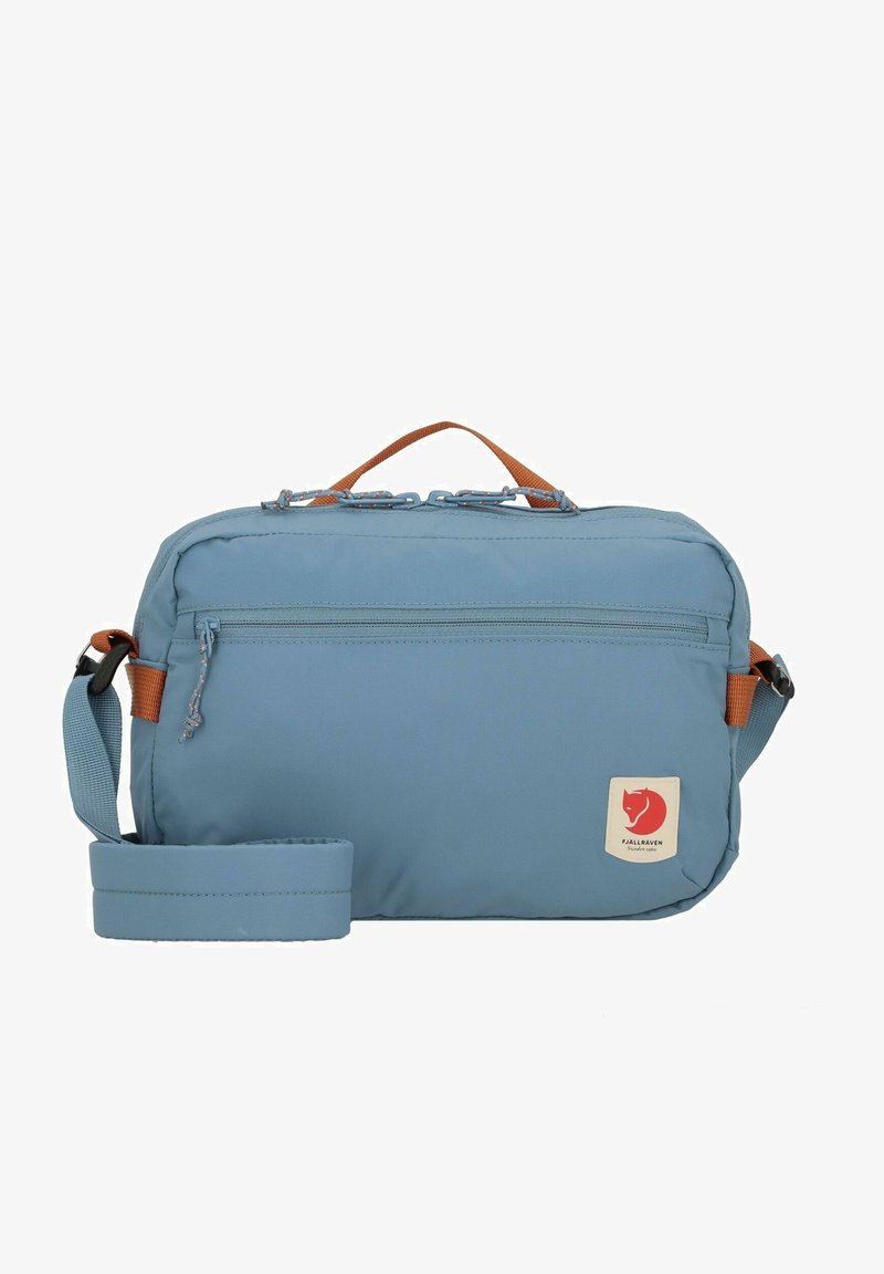 Bolsa de ombro azul céu em tecido resistente à água, com uma alça superior, uma alça ajustável e um bolso frontal com fecho e patch do logótipo.