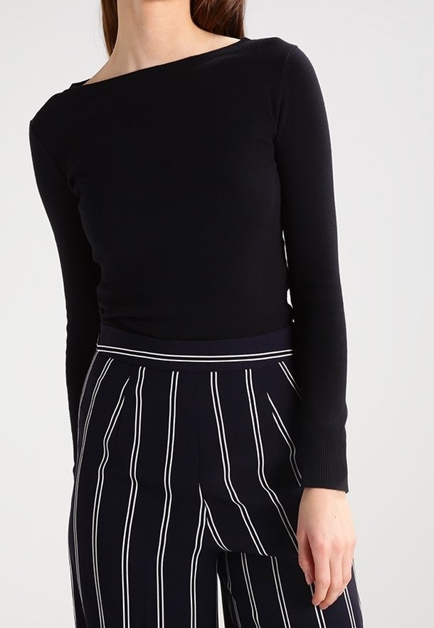 Musta, pitkähihainen pusero veneaukkokam. Valmistettu sileästä, joustavasta kankaasta. Yhdistetty tummansinisiin, raidallisiin korkeavyötäröisiin housuihin.