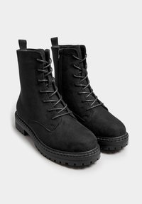Stivaletti neri con lacci, realizzati in suede con superficie texturizzata, dotati di una cerniera laterale e suola in gomma spessa con un motivo a battistrada.