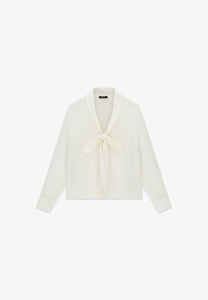 Kremowa bluzka z długim rękawem, kołnierzem szalowym i ozdobną kokardą przy dekolcie, pokazana na białym tle.