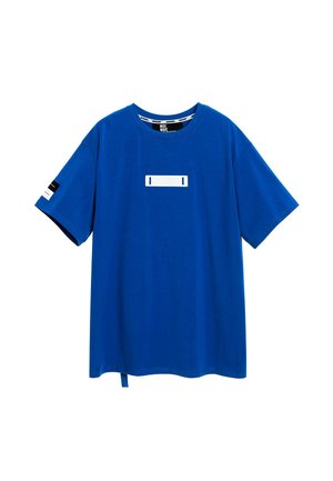 Camiseta de algodón azul con mangas cortas, que presenta un panel rectangular blanco en el centro y detalles en negro y blanco en las mangas.