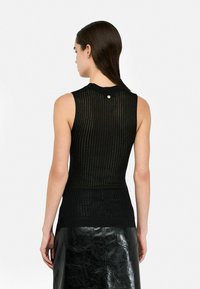 Top senza maniche nero con design a costine, che mostra una finitura testurizzata. Presenta un piccolo dettaglio con bottone sul collo sul retro.
