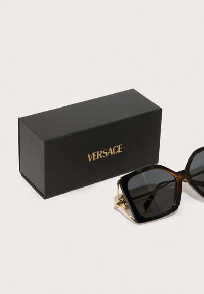 Sluneční brýle Versace s želvovinovým rámem, tmavými skly, zlatými akcenty a černou krabičkou se zlatým nápisem "VERSACE".