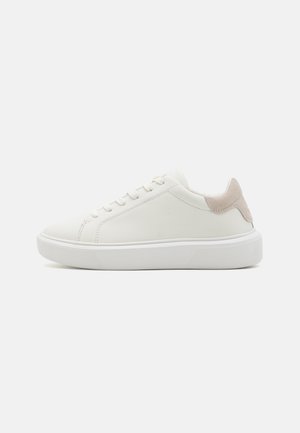 White leather sneaker with a textured beige heel accent, flat laces, and a thick white rubber sole. Minimalistic design.