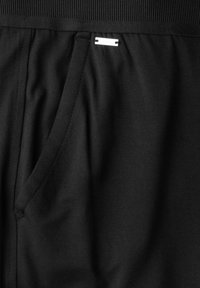 Svarta idrottsshorts i mjukt tyg, med en ribbad midjeband, sidficka och en liten metallisk logotags.