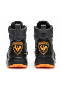 Czarne buty trekkingowe z pomarańczową podeszwą. Posiadają wyraźne logo oraz teksturowaną cholewkę z wsparciem kostki i pętlą ułatwiającą zakładanie.