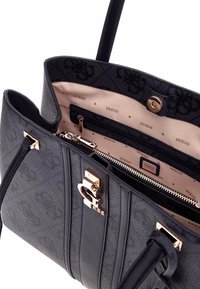 Bolso de mano texturizado negro con herrajes dorados, que cuenta con un compartimento con cremallera y un interior con marca. Incluye asas dobles y rayas verticales.
