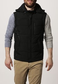 Czarna puchowa kamizelka z kapturem, wyposażona w zapinaną na zamek kieszeń na piersi, przednie guziki oraz szary podkoszulek z długim rękawem o teksturowanym wykończeniu.