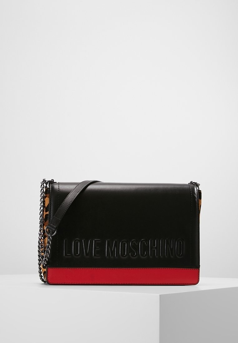 Sac à épaule Love Moschino noir avec des bords rouges, des côtés imprimés léopard et une bandoulière en chaîne posé sur une surface blanche.
