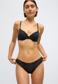 Schwarzer BH mit Spitzenbesatz und passende Bikini-Slip, aus glattem Stoff, mit verstellbaren Trägern und zarten Schleifendetails.