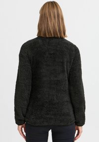 Maglione in pile nero con una superficie morbida e testurizzata, maniche lunghe e scollatura rotonda, caratterizzato da una vestibilità rilassata e orlo cucito.