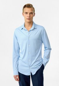 Lichtblauw overhemd met lange mouwen van gladde stof, voorzien van een puntkraag en knoopsluiting aan de voorkant, aangevuld met een slim-fit ontwerp.