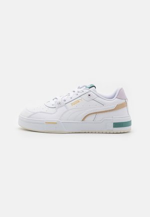 Biały niski sneaker Puma z beżowymi i zielonymi akcentami, perforowanym noskiem, wyściełanym kołnierzem i markowymi detalami po bokach i na podeszwie.
