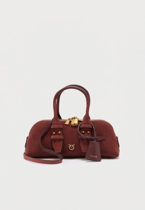 Sac à main en daim marron avec double poignée, ferrures dorées incluant un cadenas, et une bandoulière amovible sur fond blanc.