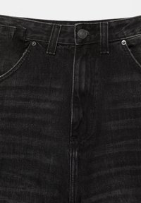 Primo piano di jeans in denim nero che mostra bottone, passanti per cintura, tasche anteriori e dettaglio della trama del tessuto.