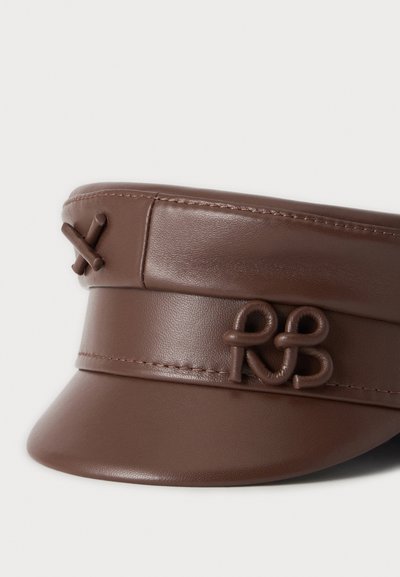 Casquette marron en cuir synthétique avec une petite visière et des boucles torsadées décoratives à l'avant et sur le côté.