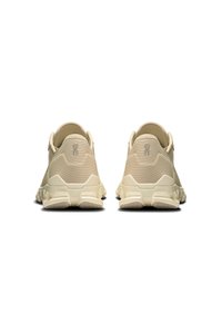 Beige træningssko med en tekstureret stofoverdel og gummisåler. Har logodetaljer og et afrundet hældesign.