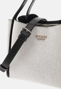 Borsa a rete argentata con dettagli in pelle nera e tracolla regolabile. Presenta una chiusura con zip e un logo dorato. Forma compatta e rettangolare.