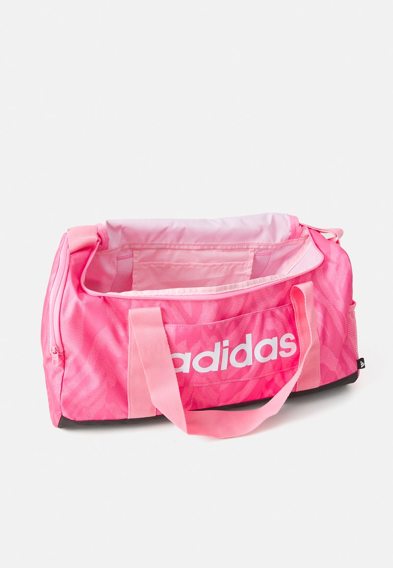 Rožinė audinio sportinė rankinė su balta logo, užtrauktuku uždaroma pagrindinė dalis, trumpos rankenos ir tekstūruotas dizainas. Juodas apačios panelis.