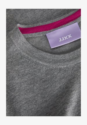 Suéter de punto gris con un cuello redondo acanalado. Acento en el cuello interno de color rosa. Etiqueta visible con "JJXX" sobre un fondo lila claro.