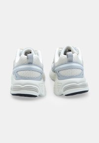 Sneakers bianchi e grigio chiaro con tessuto in rete, una suola intermedia testurizzata e un'etichetta di estrazione posteriore. Presentano un colletto imbottito e una suola in gomma.