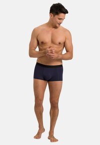 Mörkblå kalsonger i boxerstil med en svart elastisk midjeband, med en slät textur och en åtsittande design för komfort och stöd.
