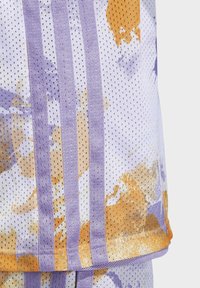 Abbigliamento sportivo in mesh viola e bianco con schemi di colore astratti in arancione, giallo e viola; include tre strisce verticali.