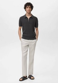 Polo de tricot gri închis cu mâneci scurte, guler cu fermoar; asortat cu pantaloni bej deschis și sandale negre. Textură netedă și design potrivit.