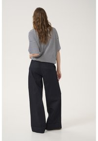 Top a righe a maniche corte con una vestibilità rilassata, abbinato a pantaloni in denim scuro a gamba larga con orli piegati e tasche posteriori.
