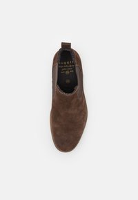 Zapato marrón de ante tipo slip-on con paneles elásticos laterales, punta redondeada y suela texturizada. Presenta un logotipo en el interior y un forro suave. Talla 42.