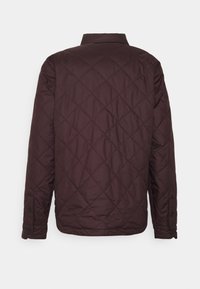 Bordová prošívaná bunda s diamantovým vzorem, s knoflíkovými manžetami a límcem. Hladká textura, navržena pro teplo a pohodlí.