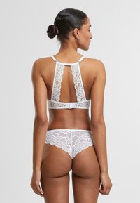 Hvit blonde bralette og truse-sett med blomstermønster, justerbare stropper og racerback-design. Myk tekstur, detaljert blondekant.