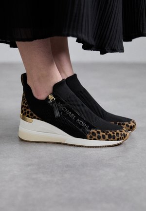 Baskets chaussettes noires avec un accent imprimé léopard, des détails en métal doré, et une tige texturée à enfiler.