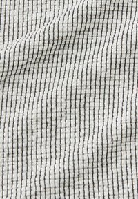 White textured fabric with small black vertical grid lines creating a subtle wavy pattern across the surface.