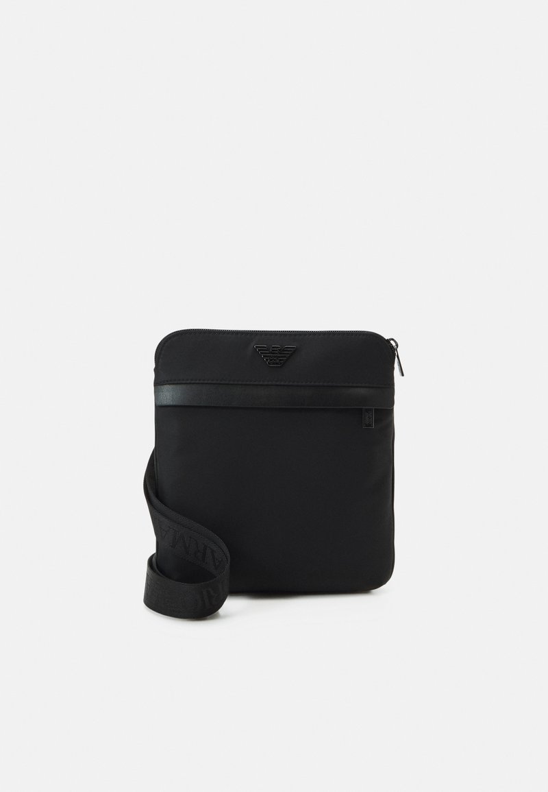 Borsa a tracolla nera in nylon con zip, design piatto e logo in rilievo sul davanti. Dotata di una tracolla intrecciata.