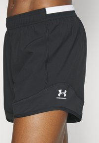 Pantalones cortos deportivos negros con una cinturilla elástica oculta, con un logo de Under Armour en blanco y detalles de costuras en contraste. Material suave y ligero.