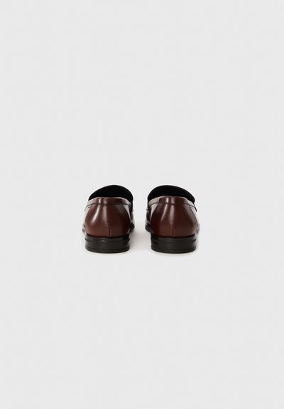 Bruna läderloafers med en slät finish, med rundad tå och en låg, svart gummisula. Inga synliga detaljer eller metallaccenter.