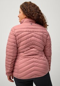 Lyserød pufferjakke med chevron-quilting, høj krave og subtilt logodetalje på ryggen. Glat, let materiale.