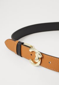 Cintura in pelle con una tracolla testurizzata color beige, retro nero e hardware dorato con un design di chiusura unico.