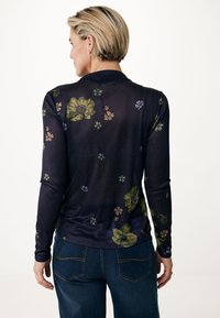 Långärmad skjorta i marinblått tyg med livliga blommönster i grönt, orange och lila, med en mjuk textur och slim fit.