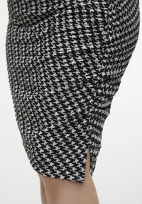Čierno-bielá sukňa s potlačou houndstooth, vyrobená z texturovanej tkaniny, úzkeho strihu a so zavedeným detailom na strane.