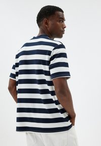 Stribet T-shirt med marineblå og hvide vandrette striber, lavet af bomuldsstof, med en afslappet pasform, korte ærmer og rund halsudskæring.