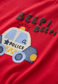 Red fabric with an embroidered police car design featuring blue accents, yellow circular details, and the text "BEEP! BEEP!" in black.